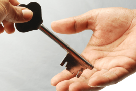 A hand passing a large golden key to another hand