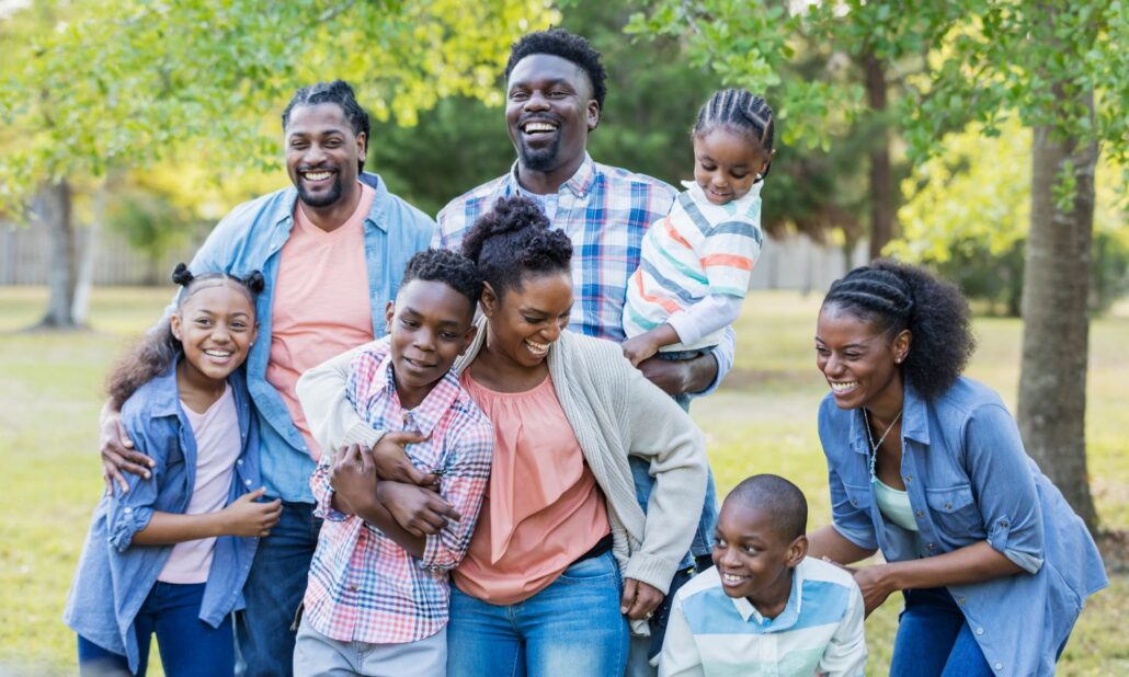 Smiling blended family standing close together outdoors.