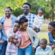 Smiling blended family standing close together outdoors.