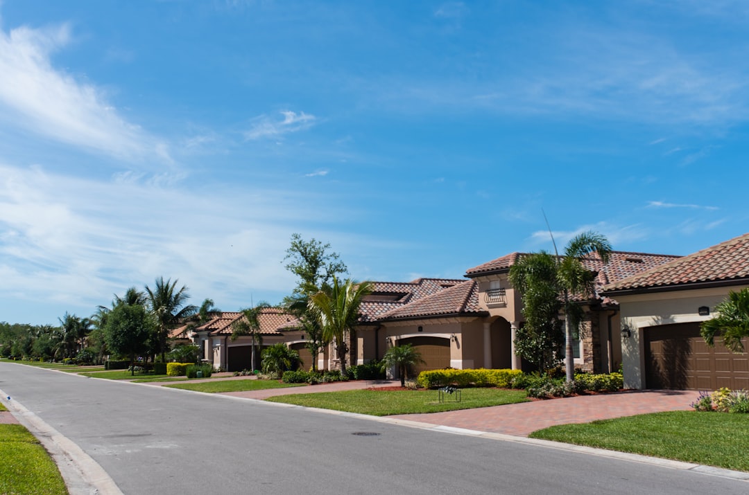 A clean, wide shot of a row of diverse modern suburban homes under a bright blue sky, illustrating the scope of the state-by-state real estate market.