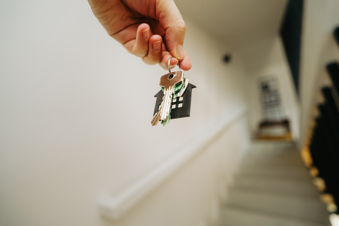A close-up of a set of modern house keys resting on a stack of official documents, representing the final step of meeting real estate license requirements.
