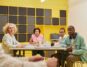 Diverse group of professionals sit around a modern conference table, collaborating and reviewing documents, representing a...