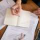 Person sits at a clean, modern desk, carefully reviewing a real estate contract with a pen and calculator, symbolizing fin...