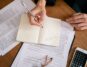 Person sits at a clean, modern desk, carefully reviewing a real estate contract with a pen and calculator, symbolizing fin...