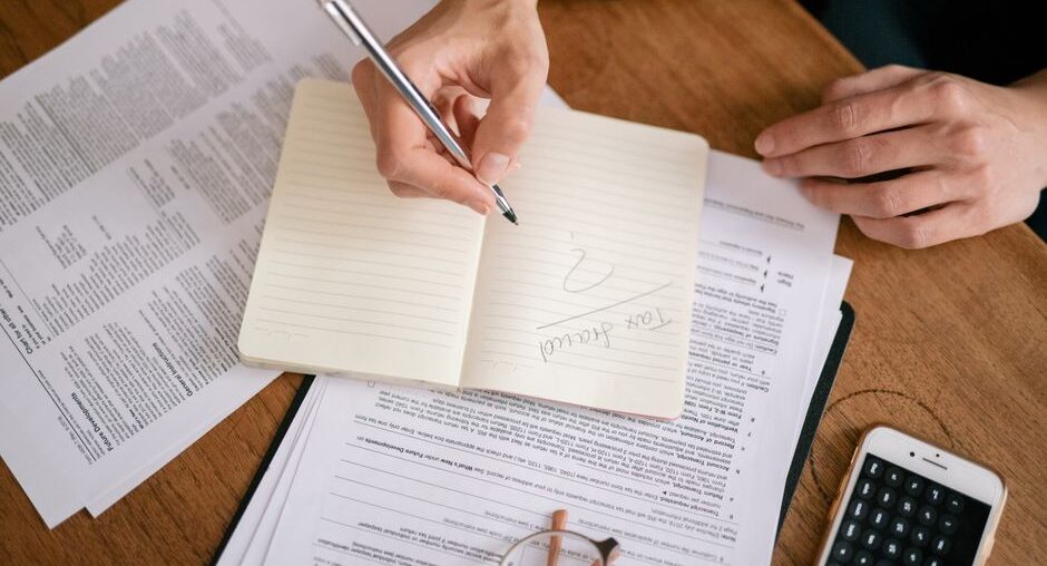 Person sits at a clean, modern desk, carefully reviewing a real estate contract with a pen and calculator, symbolizing fin...