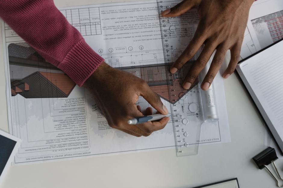 A set of modern house keys resting on top of architectural blueprints spread across a clean, professional desk, symbolizing the path to a real estate career.