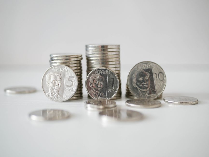 A small white house model rests on a neat stack of coins against a bright, minimalist background, visually representing the concept of protecting home equity.