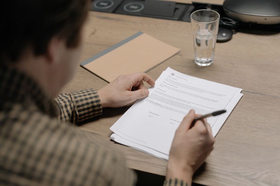 A close-up, professional shot of a magnifying glass held over a real estate contract, focusing on the fine print to symbolize the legal scrutiny required to find hidden fees.