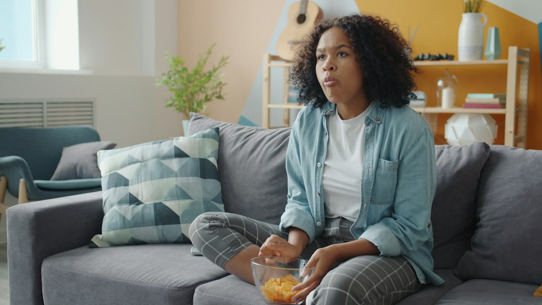 A professional woman reviews information on a tablet in a modern, brightly lit living room, symbolizing innovative real estate technology.